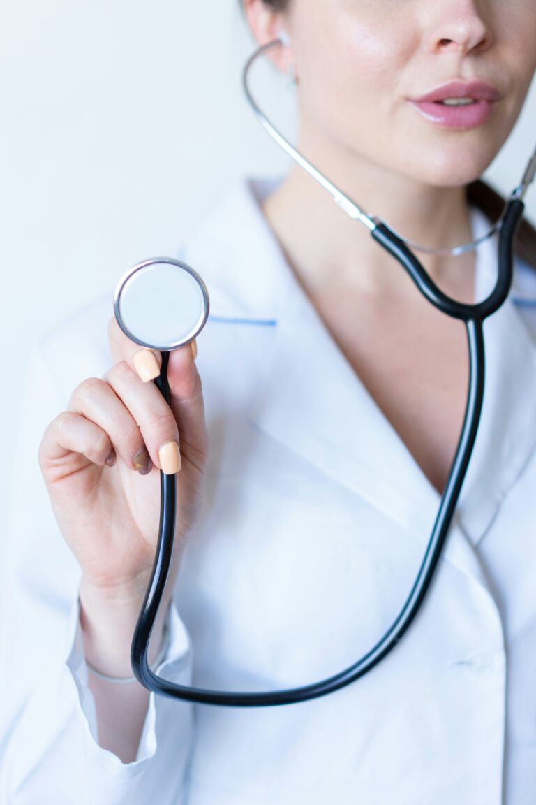 female woman wearing a doctor coat and has a stethoscope in her ears and is holding it up with her hand. preventative care