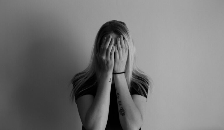 Blonde young woman with hands covering her face. sexual assault