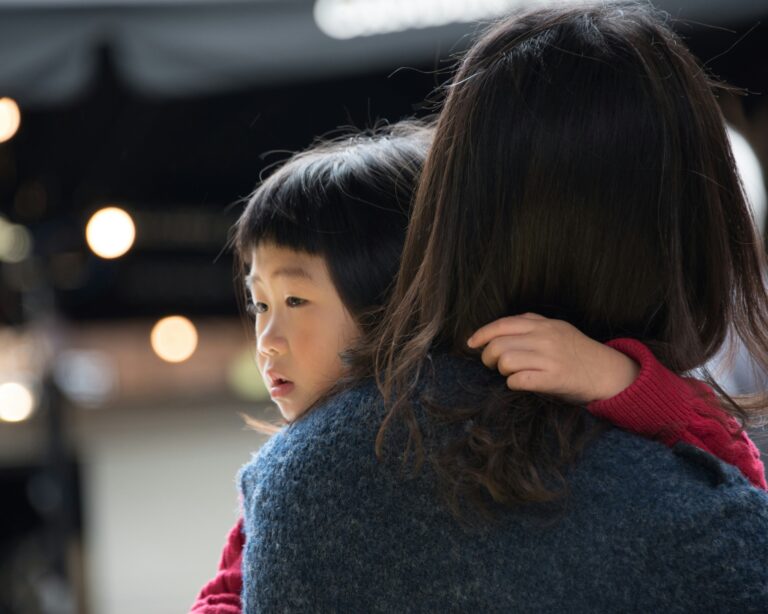 young girl in her mothers arms giving her a hug.