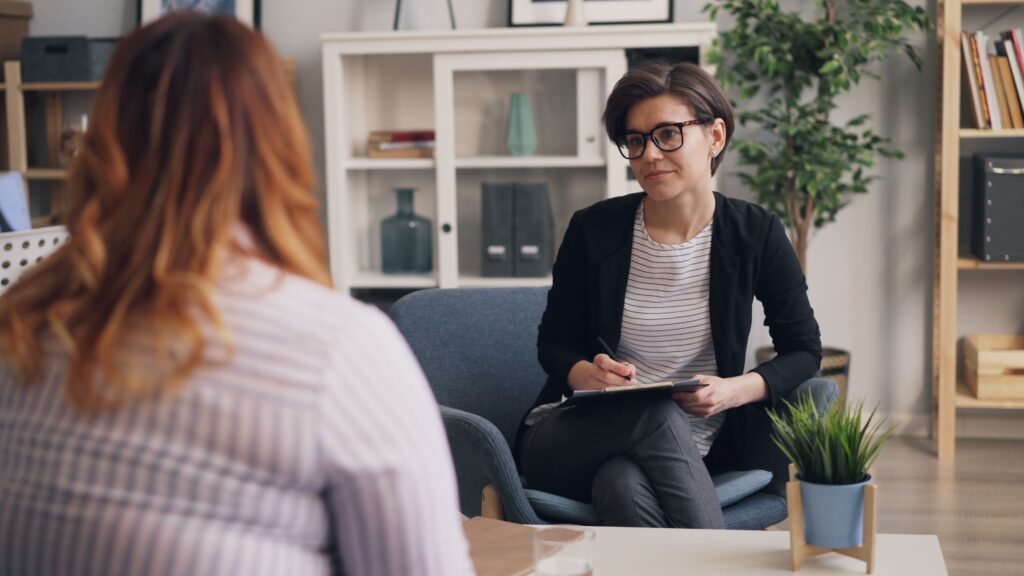 a provider sits in a comfortable office taking notes during a patient session